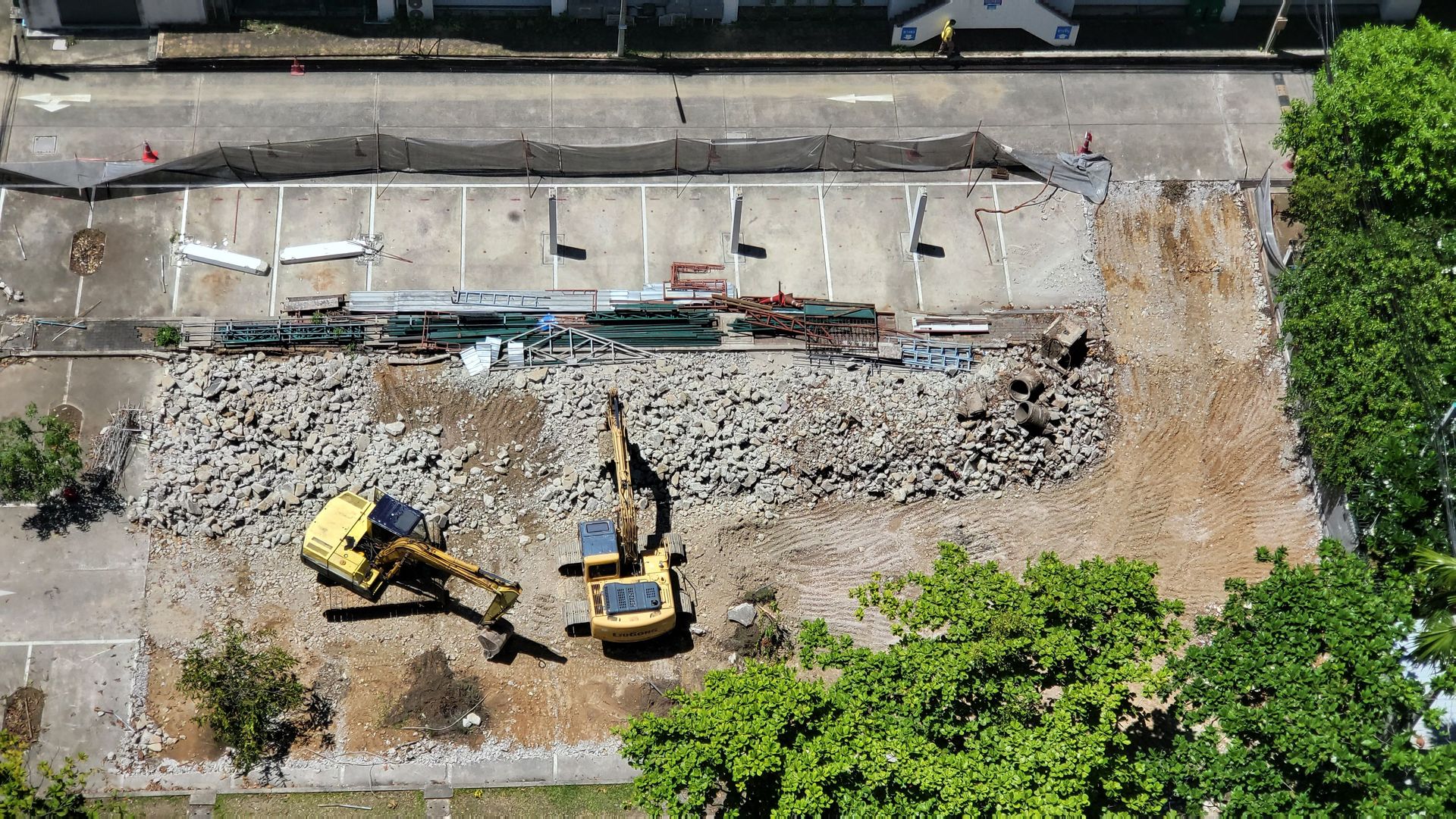 Aerial shot of an urban construction site with excavators moving debris and dirt.