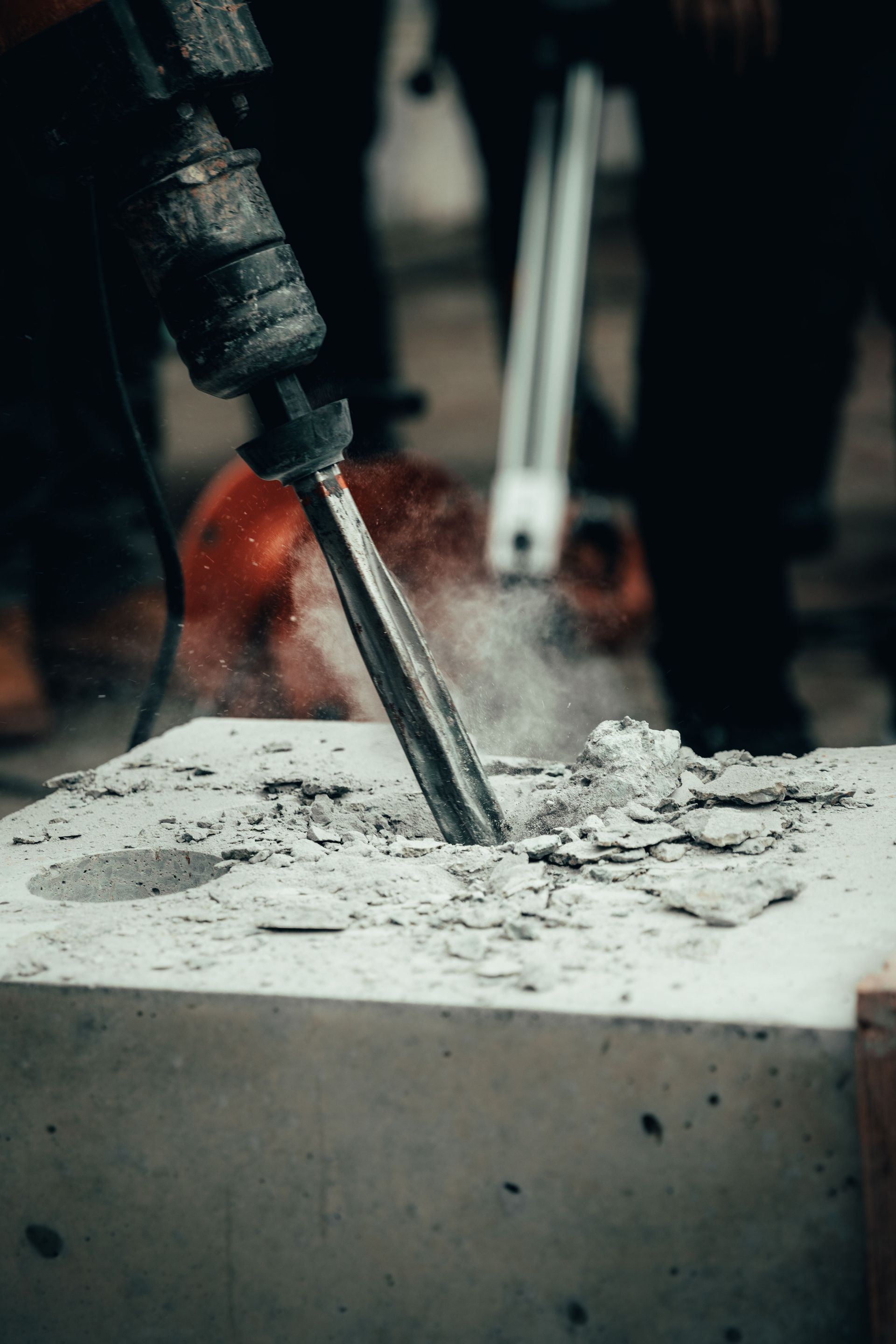 A detailed close-up of a power tool chipping away at a concrete block, capturing action and dust.